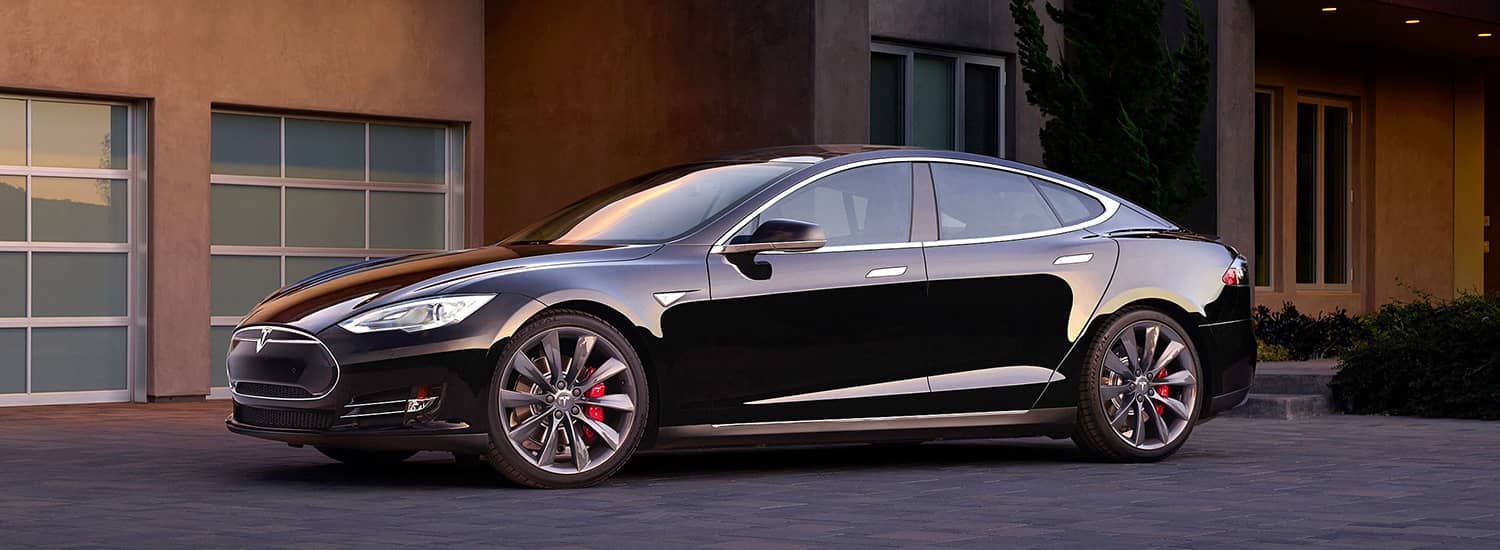 Black early Tesla Model S parked outside a building