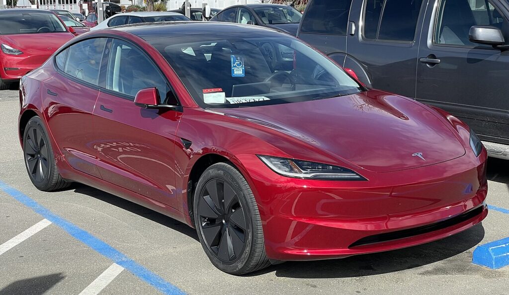 Red Tesla Model 3 showing its front bumper and painted panels