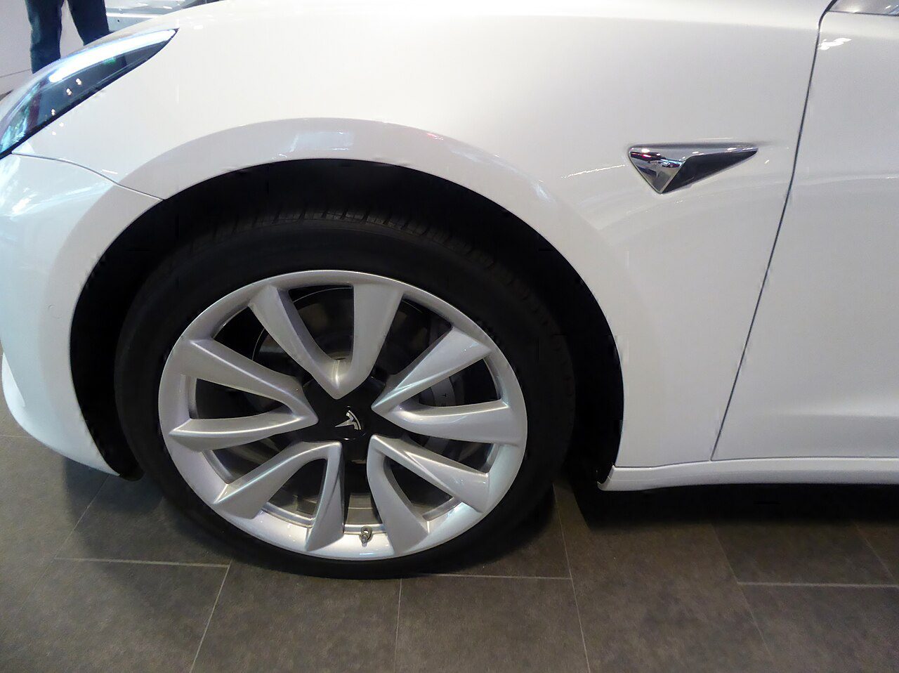 Front wheel and tire on a white Tesla Model 3
