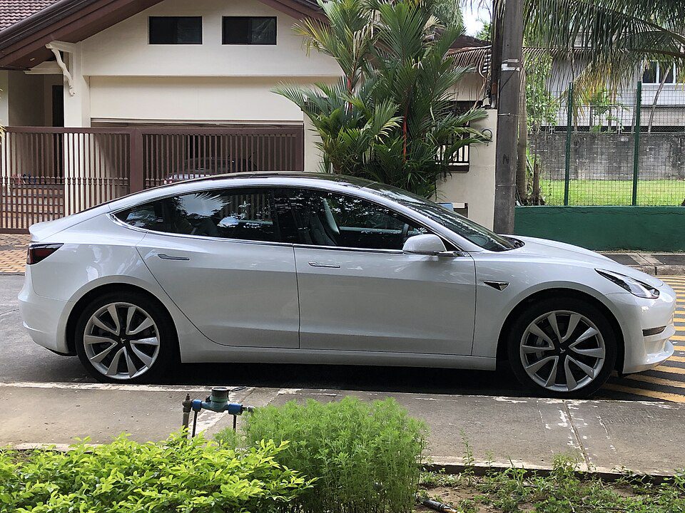 Side profile of a silver Tesla Model 3 showing the area below both doors