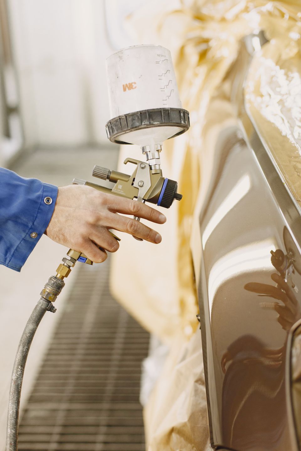 Spray gun applying paint to a vehicle panel