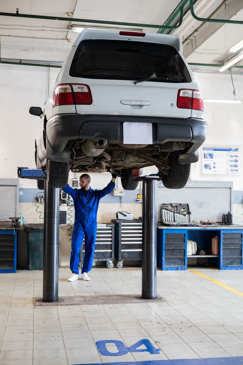 Mechanic examining the underside of a raised SUV