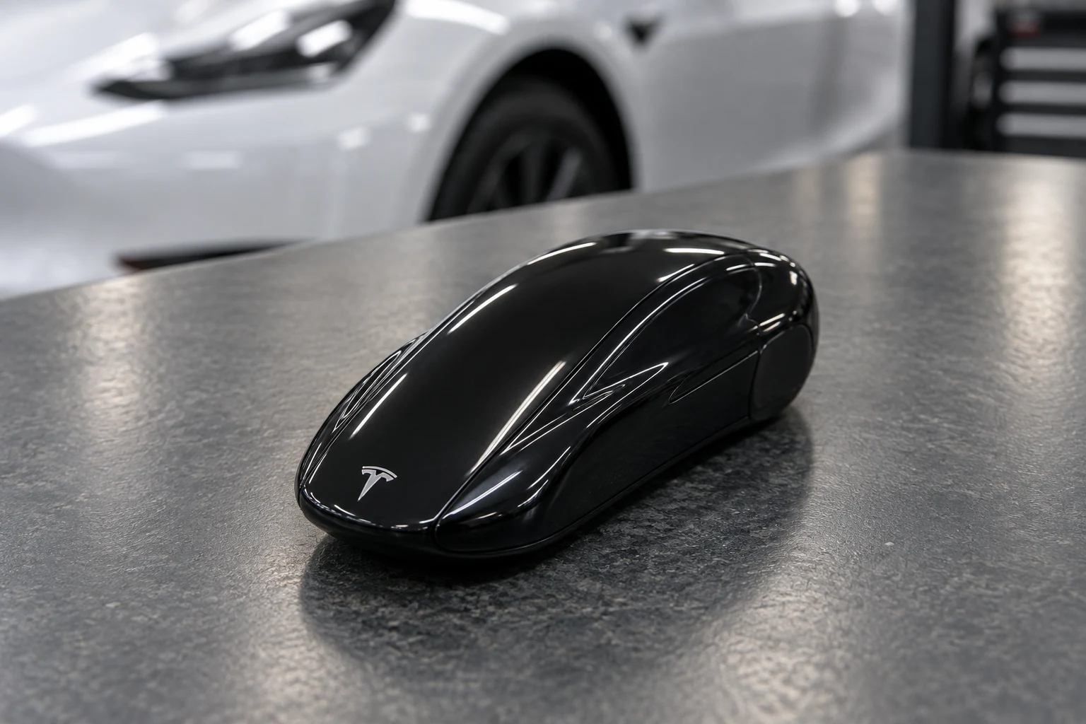 Black car-shaped Tesla key fob on a workshop counter