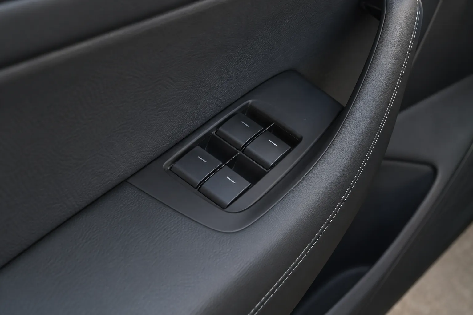 Four window switches on a black driver door panel